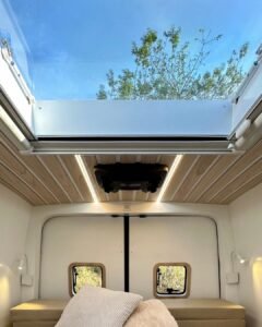 Sala multifuncional da Sprinter 416 Extra Longa, com sofá-cama e mesa retrátil, em design moderno.