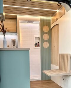 Entrada da Sprinter 416 Extra Longa, com detalhes em madeira clara e iluminação LED, em design moderno.