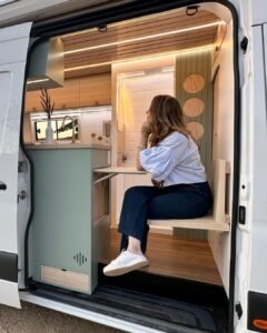 Área de entrada da Sprinter 416 Extra Longa, com mesa retrátil e banco embutido, em design moderno.