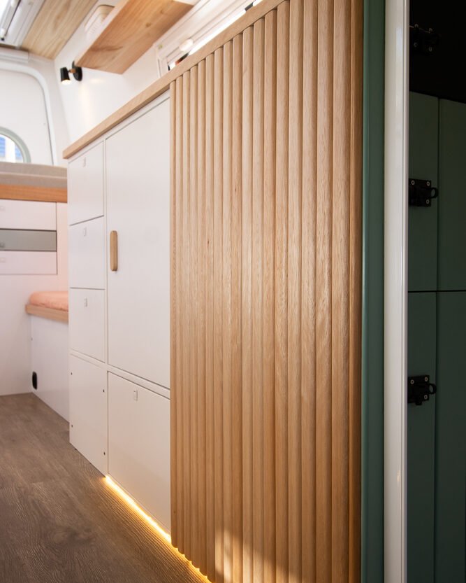 Móveis com acabamento em madeira clara no interior da Sprinter 416 Extra Longa, em design moderno e funcional